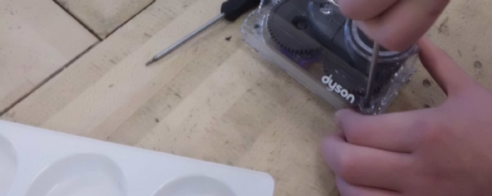 hands using a screwdriver on a dyson hoover